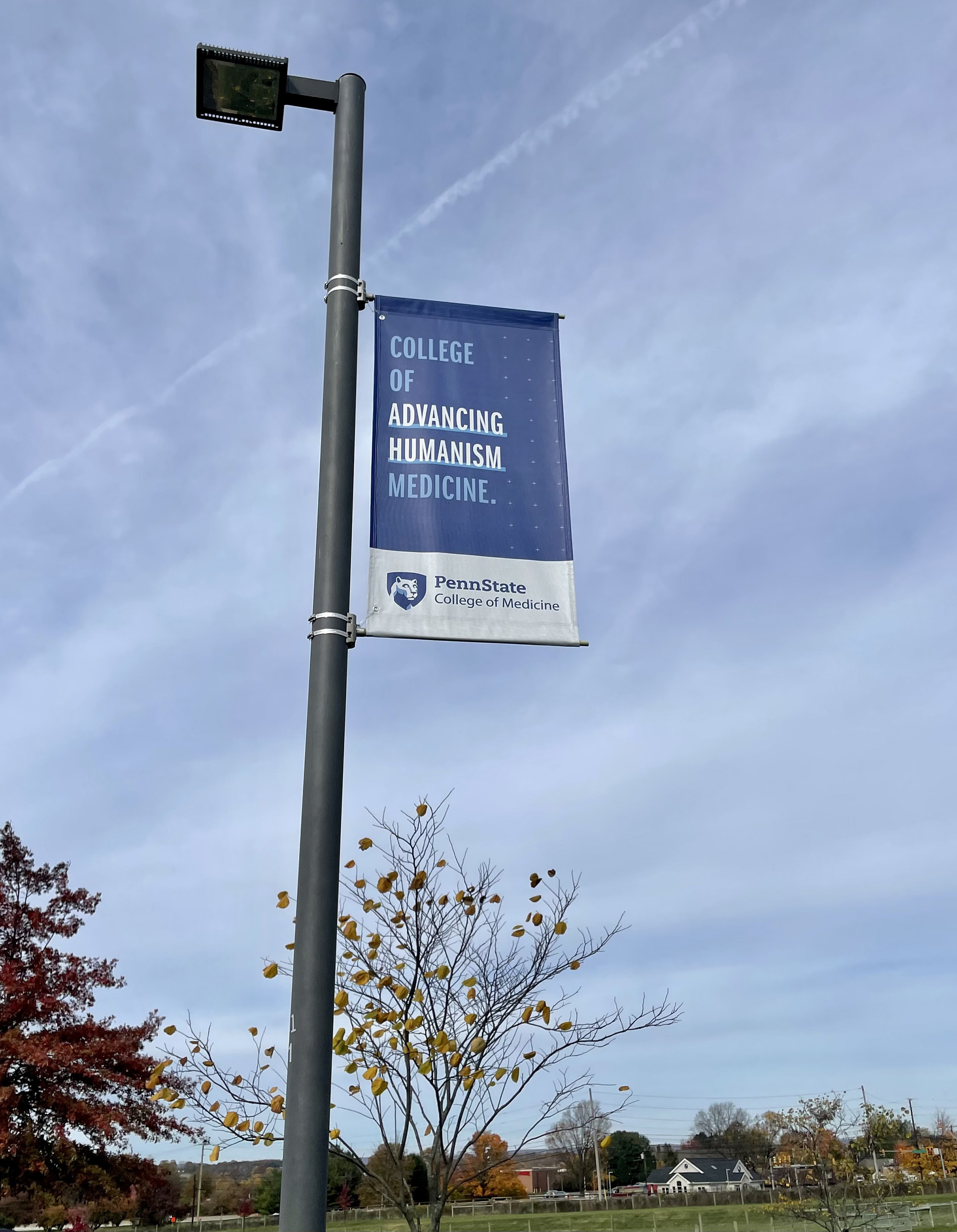 A banner on a light pole outdoors says College of Advancing Humanism Medicine